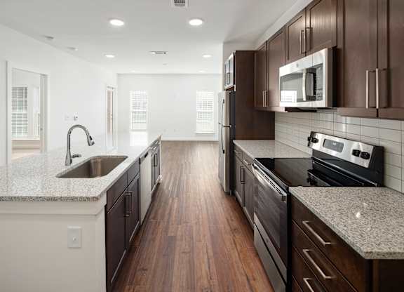 A large kitchen with granite counter top and brown cabinets.