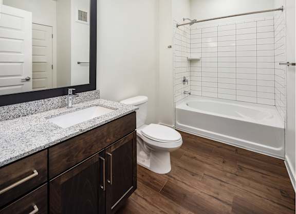 bathroom with granite countertop and white toilet and shower