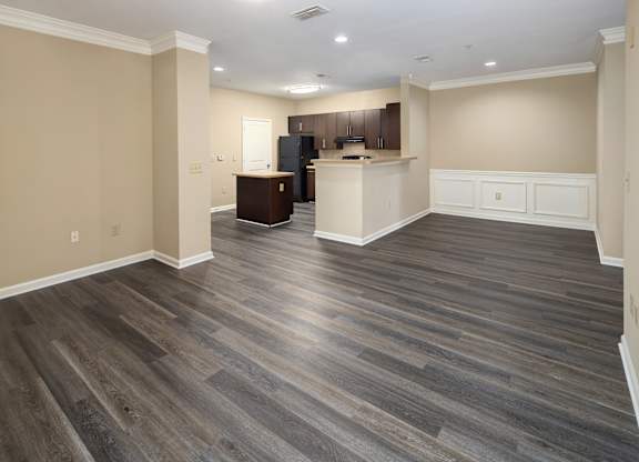A spacious room with wooden flooring and a kitchen area.