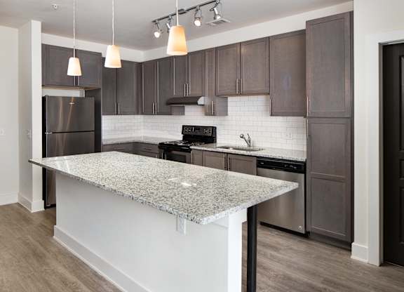 A kitchen with a granite countertop and dark brown cabinets.