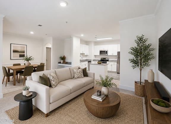 A living room with a white couch, a coffee table, and a dining table.