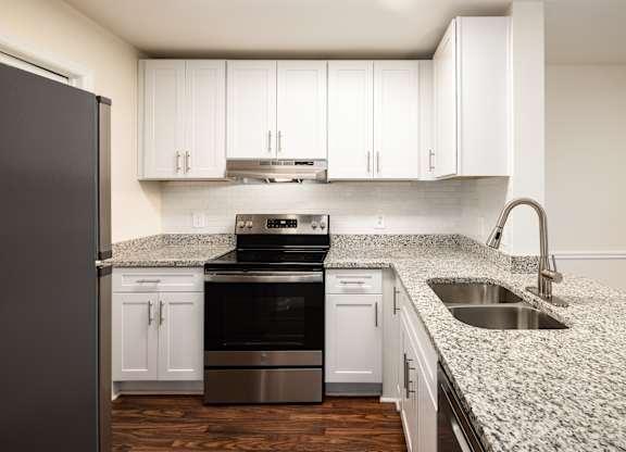 A kitchen with a granite countertop and stainless steel appliances.