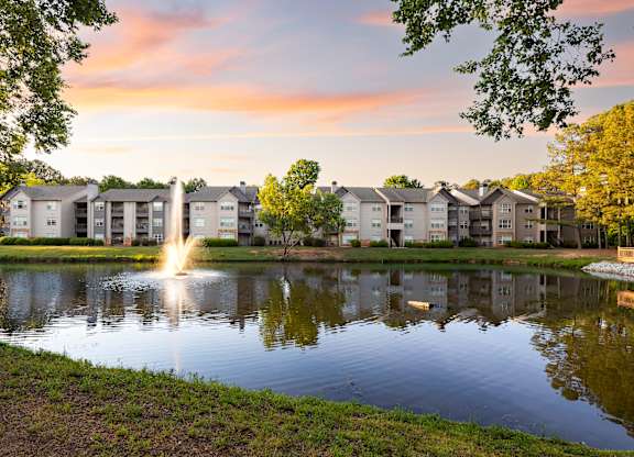 A serene pond surrounded by residential buildings with a fountain in the middle.