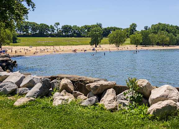 A beach scene with people swimming and a rocky shore.