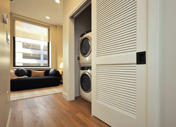 A modern laundry room with a washer and dryer built into a wall.