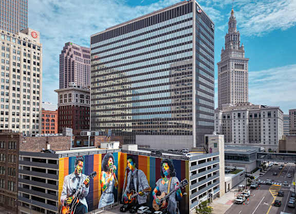 A cityscape with a large building in the center and a mural on the side of a building.