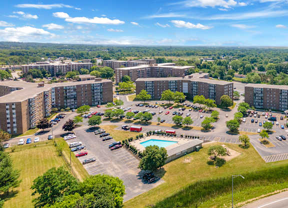 A large apartment complex with a parking lot and pool.