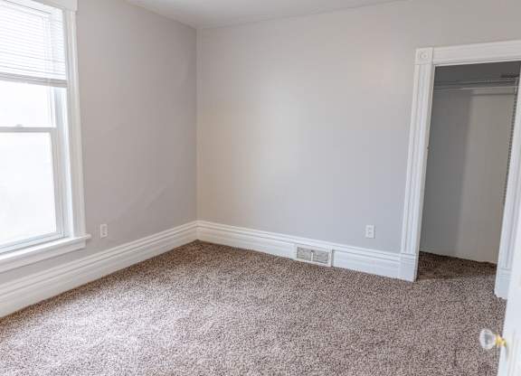 A room with a window and carpeted floor.