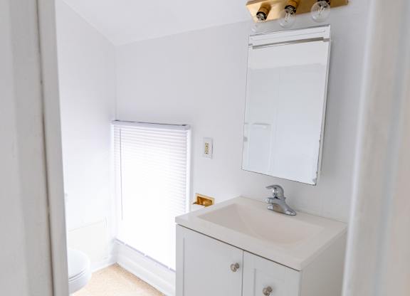 A white bathroom vanity with a mirror above it.
