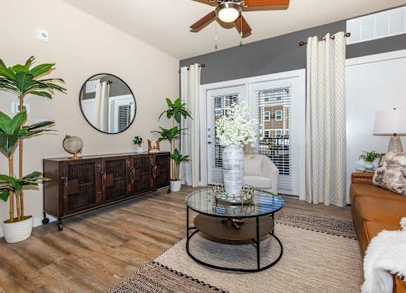 A living room with curtains, a glass coffee table and a brown couch.