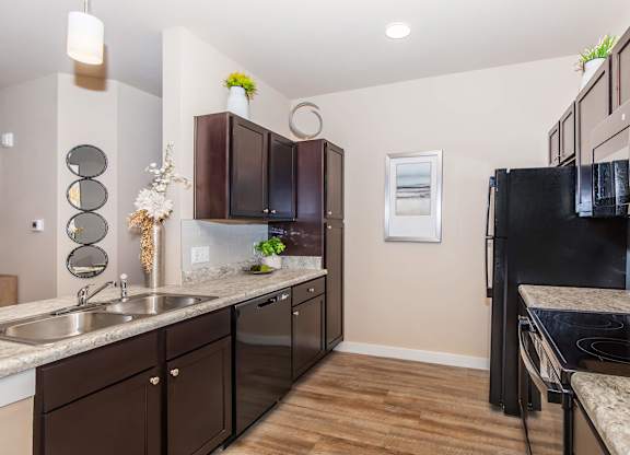 A kitchen with brown cabinets and a black refrigerator.