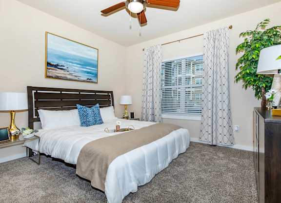 A bedroom with a large bed and a ceiling fan.