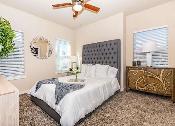 A bedroom with a bed, dresser, and ceiling fan.