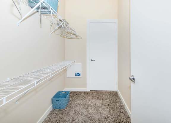 A white door is in a hallway with a carpeted floor and a basket on the floor.