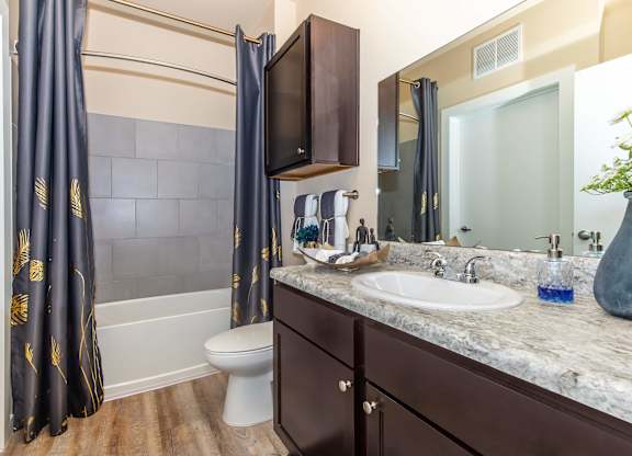 A bathroom with a white toilet, a sink, and a shower with a black curtain.