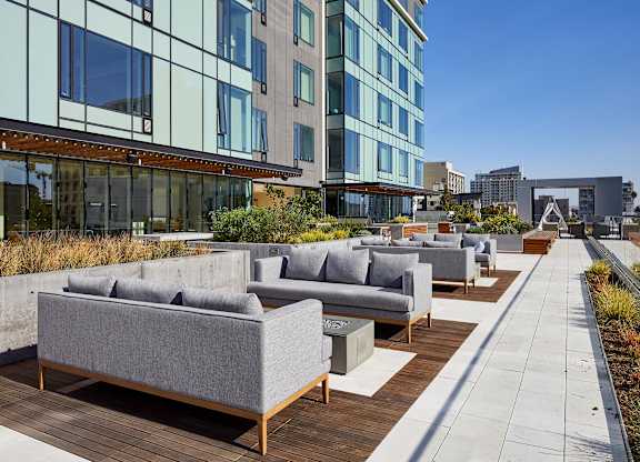 A patio with grey couches and wooden tables.