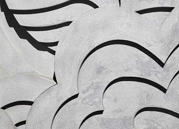 A close up of a white and black patterned artwork on the wall.