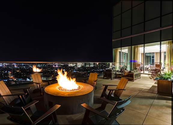 A fire pit sits in the middle of a patio with chairs around it.