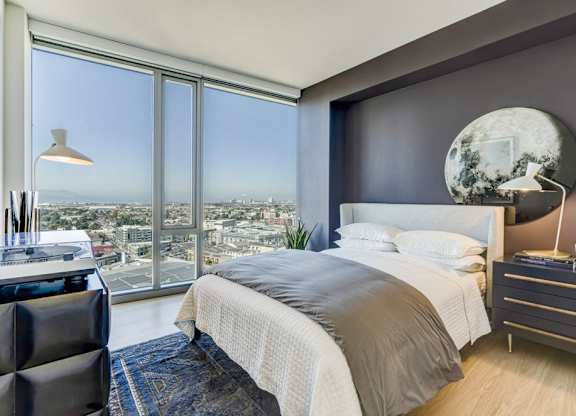 A modern bedroom with a large bed and a view of the city.