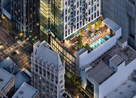 A tall building with a green roof is surrounded by other buildings.