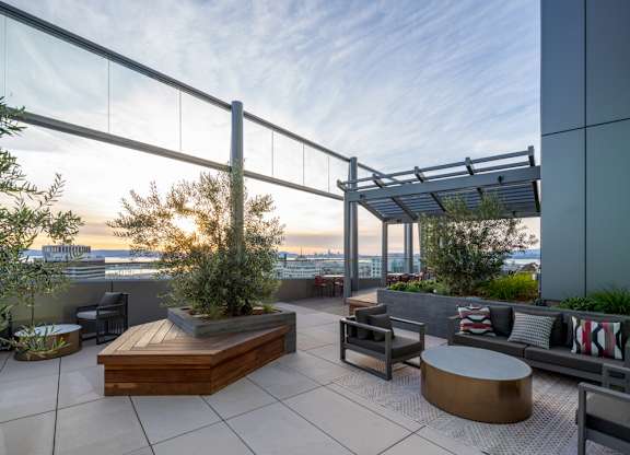 A rooftop patio with a table, chairs, and a bench.