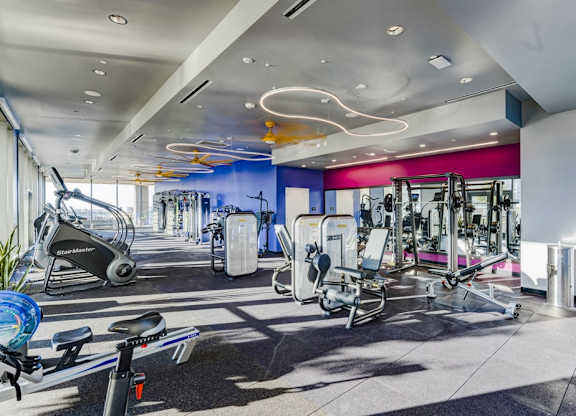 A gym with a variety of equipment including treadmills, stationary bikes, and weight machines.