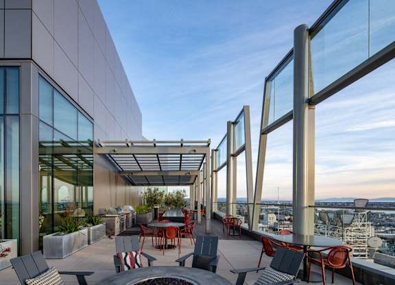 A rooftop patio with a table and chairs overlooking a cityscape.