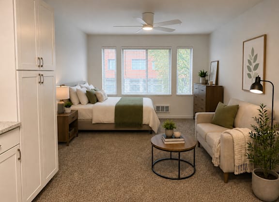 A bedroom with a bed, a couch, and a ceiling fan.