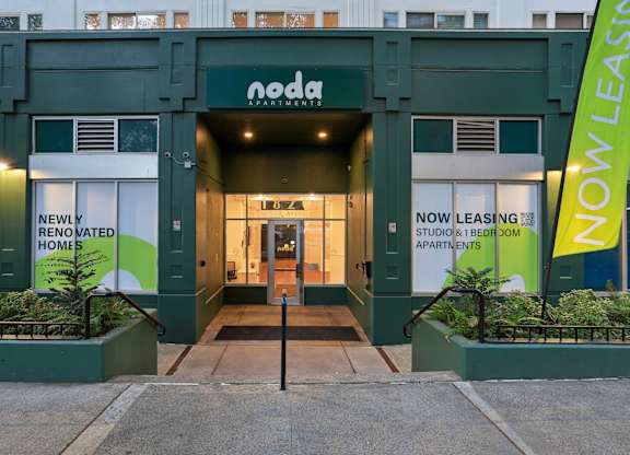 The front of a NoDa Apartments building with a sign that says "Now Leasing".