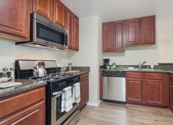 A kitchen with dark wood cabinets and a black stove top.at Norwalk Metropointe, California  