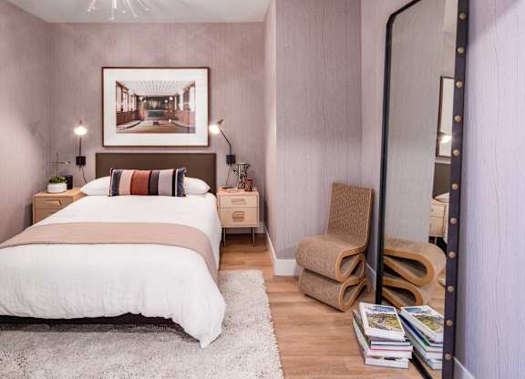 A bedroom with a large bed and a chair.