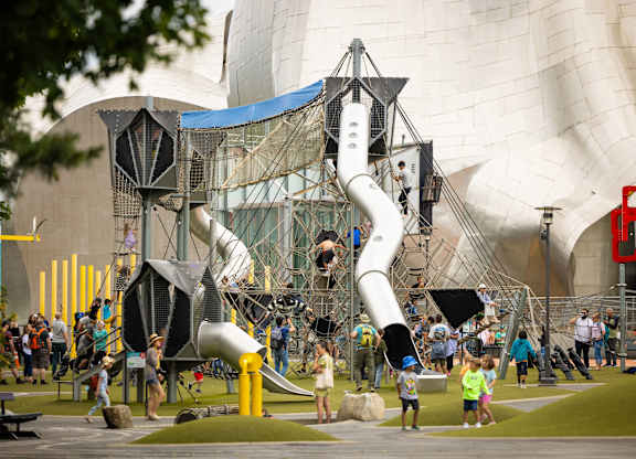 Large playground structure with modern architecture backdrop at Axis Seattle Apartments, Washington, 98109