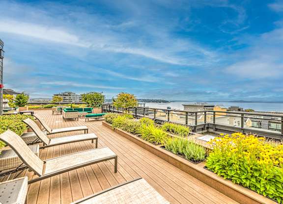 Rooftop deck with lounge chairs and water view at Axis Seattle Apartments, Washington, 98109