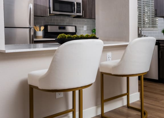 a kitchen with two white chairs in front of a counter