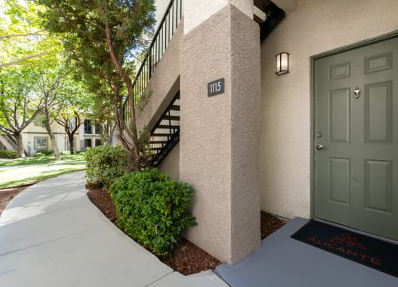 the front door of an apartment building with a sidewalk and a green door