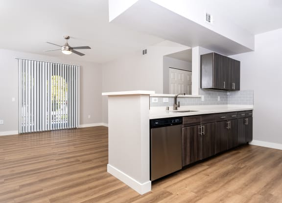 an open living room with a kitchen and a ceiling fan