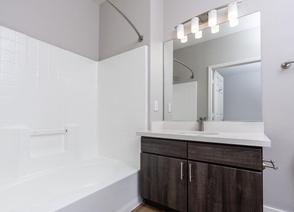 a bathroom with a white tub and a sink and a mirror