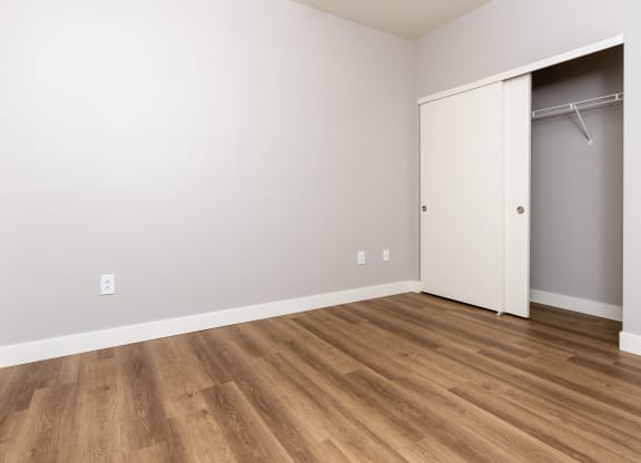an empty room with a closet and wood flooring