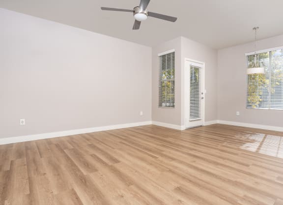 an empty living room with wood floors and a ceiling fan