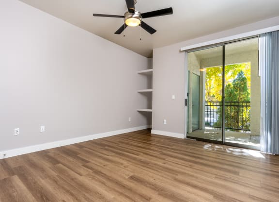 an empty living room with a ceiling fan and a sliding glass door