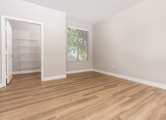 an empty room with wood flooring and a closet
