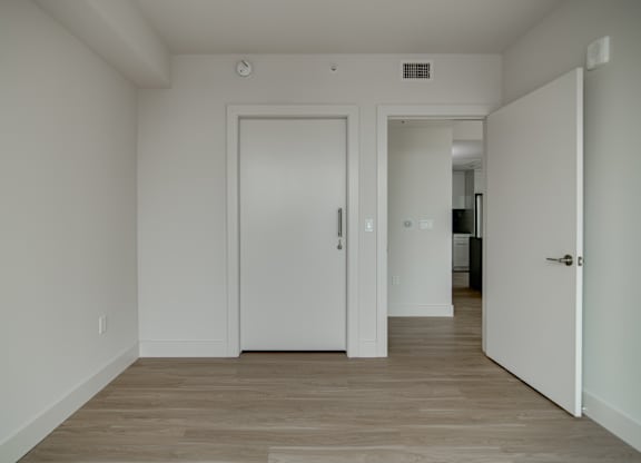 A white door is in a room with wood flooring.