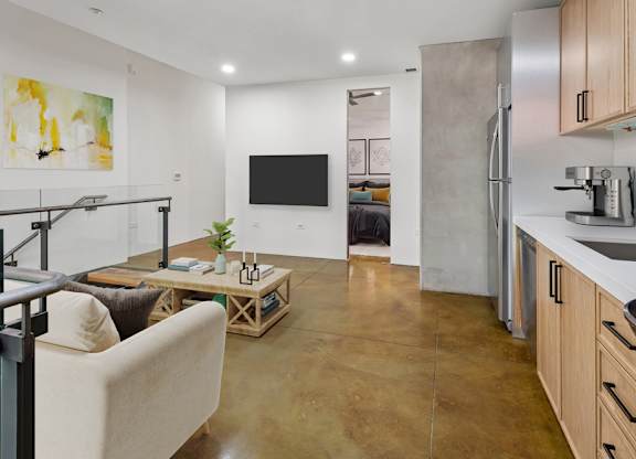 A modern kitchen with a refrigerator, sink, and a living area with a couch and a coffee table.