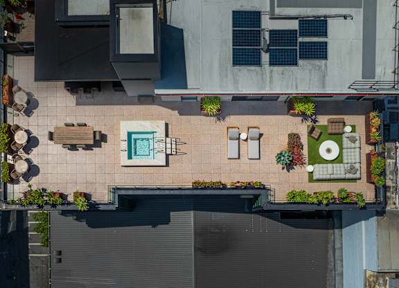 A rooftop patio with a table and chairs and a pool.