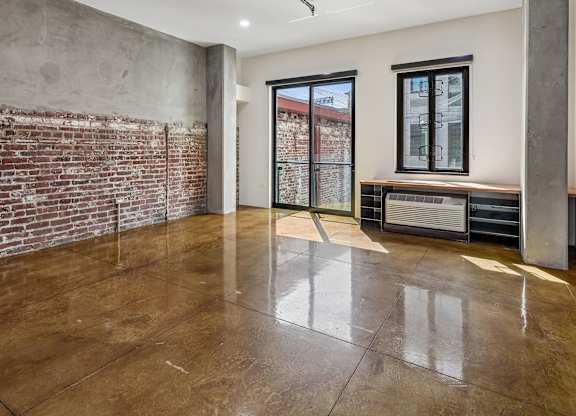 A room with a brown floor and a brick wall.
