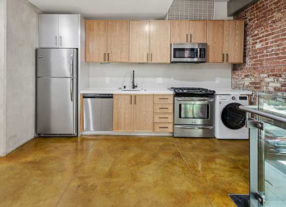A kitchen with a refrigerator, microwave, oven, and sink.