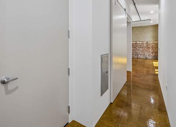 A hallway with a white door and a brick wall in the background.