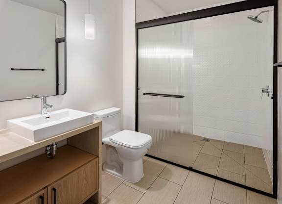 A white toilet is in a bathroom with a sink and mirror.