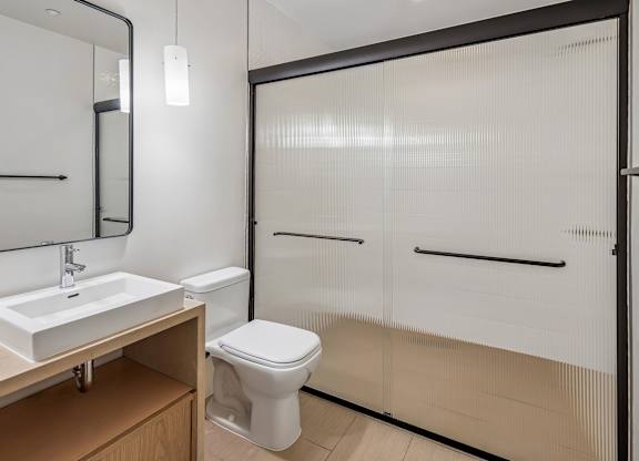 A white toilet sits in a bathroom next to a sink and a mirror.