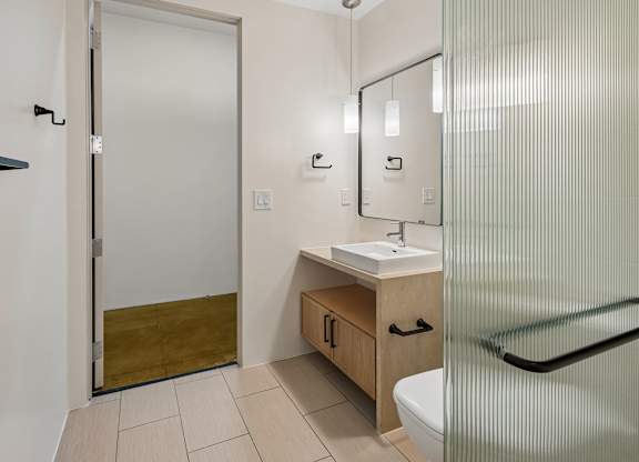 A bathroom with a sink, mirror, and shower.